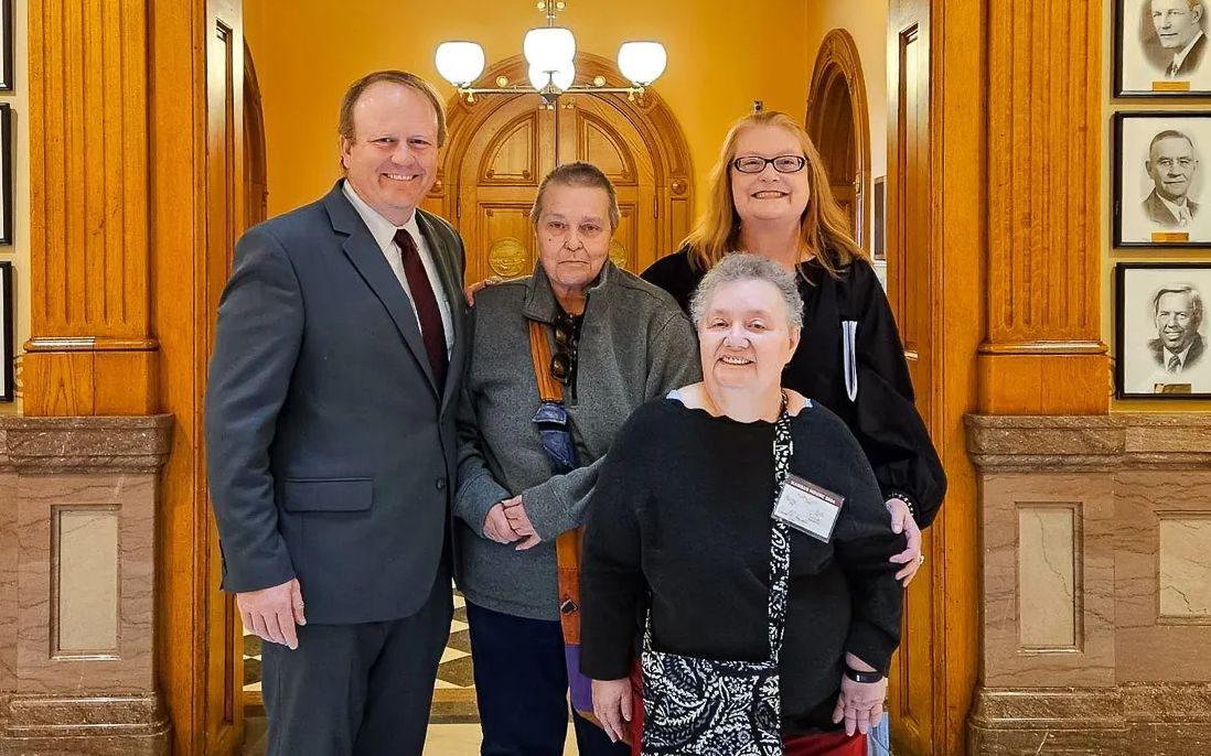 Photo taken at the Kansas Capitol on March 25, 2024. The bill’s namesake, Kathy Lobb, in front. Behind, from left to right is Mike Burgess (Disability Rights Center of Kansas), Stephanie Sanford (Self Advocate Coalition of Kansas) and Angie Reinking (Arc of Douglas County). Photo via the Lawrence Times